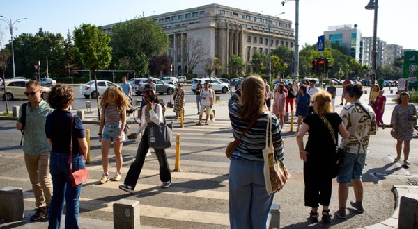 București, România – 25 iunie 2024: Oamenii traversează strada în apropierea Palatului Victoria, care găzduiește sediul Guvernului României, în București.