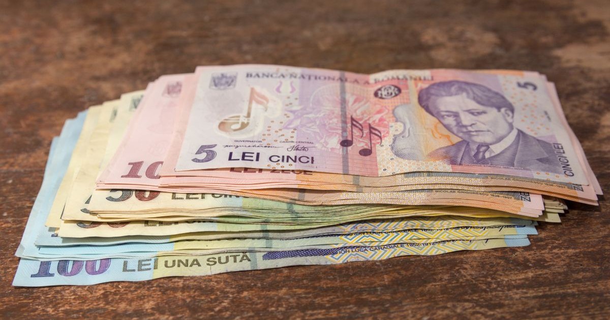 Bani pe o masă, mai multe bancnote de 5, 50 și 100 de lei pe o masă de culoare maro