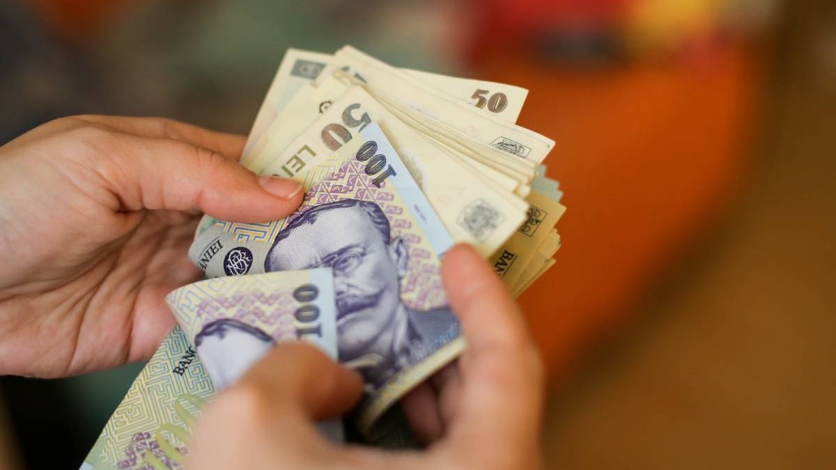 O femeie în vârstă în timp ce numără bani cash, hârtii de 50 și 100 de lei