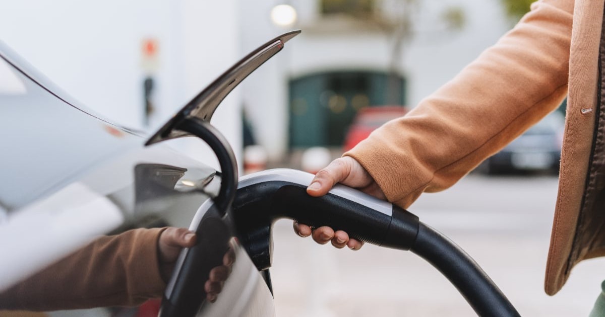 Un bărbat care încarcă o mașină electrică.