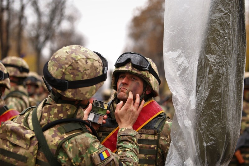 Un militar îl „camuflează” pe colegul său înainte să înceapă parada
