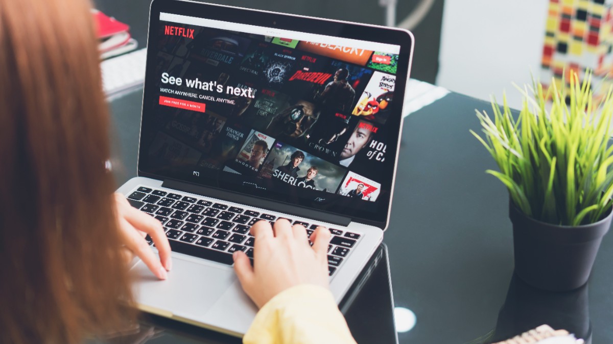O femeie care se uită la un serial pe Netflix, la laptop, așezată la birou