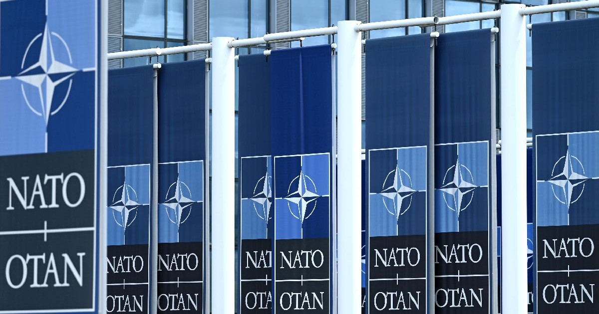 Sigla NATO pe mai multe steaguri.