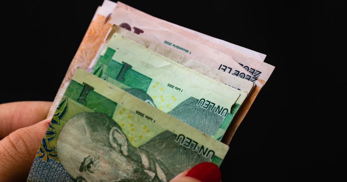 O femeie numără bani, bancnote românești, pe un fundal negru