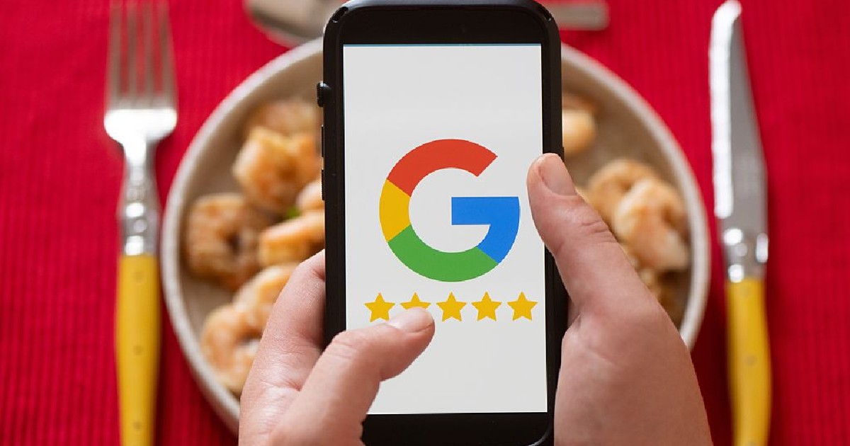 O femeie ține în mână un smartphone cu logo-ul Google în fața unei mese pregătite pentru cină.