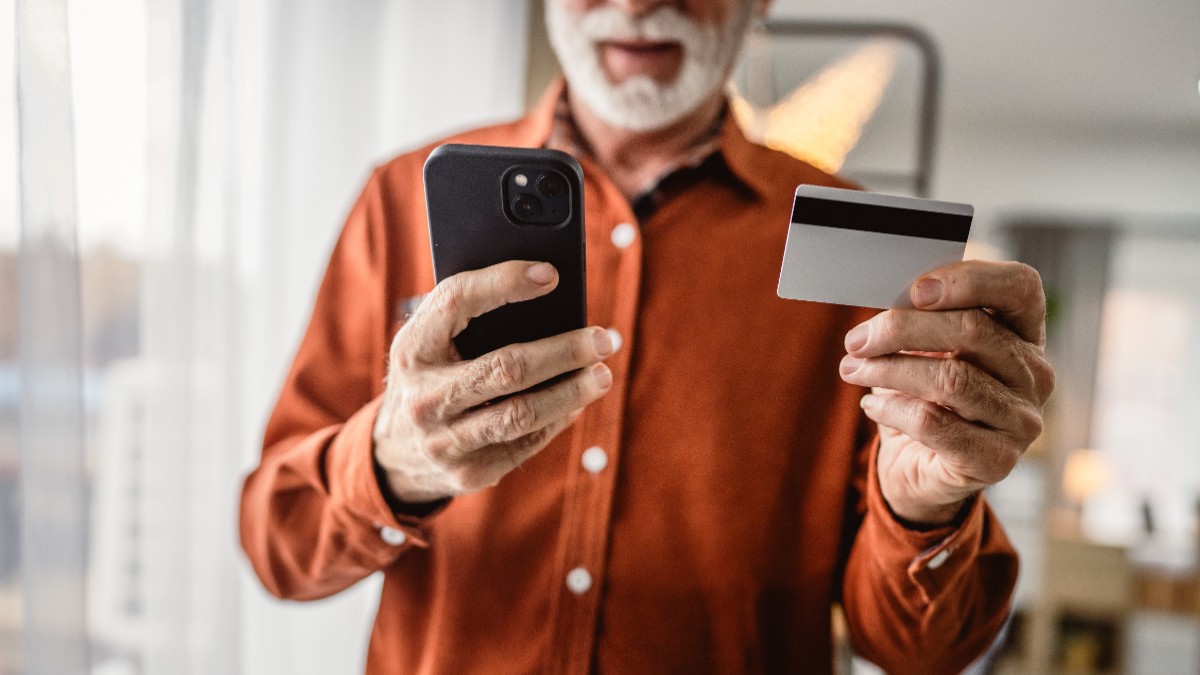 Un bărbat care ține în mâini un card și un telefon.