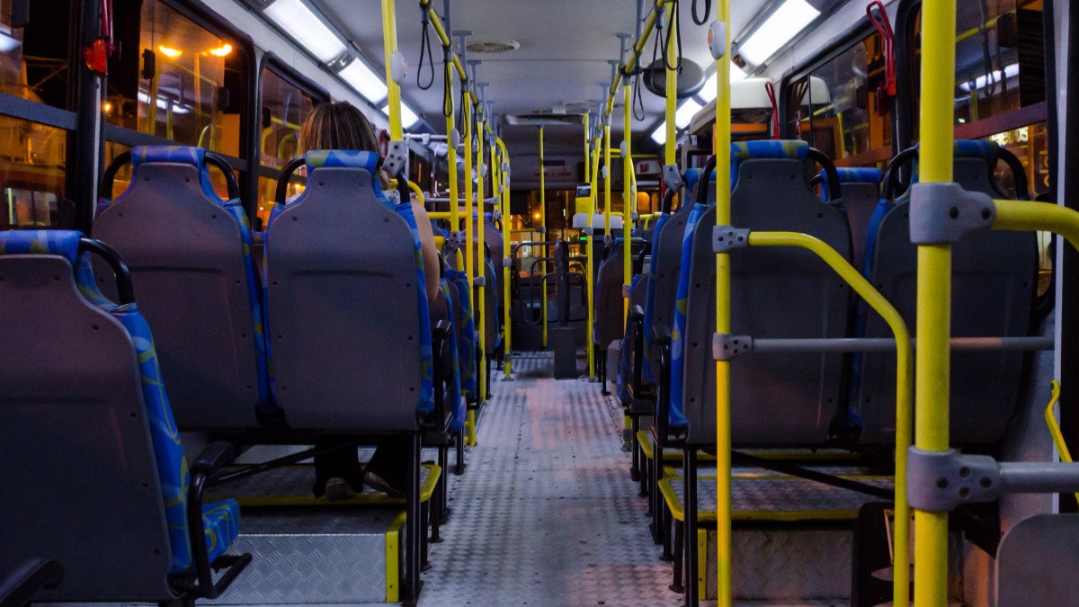 Interiorul unui autobuz aproape gol, care circulă pe timp de noapte.