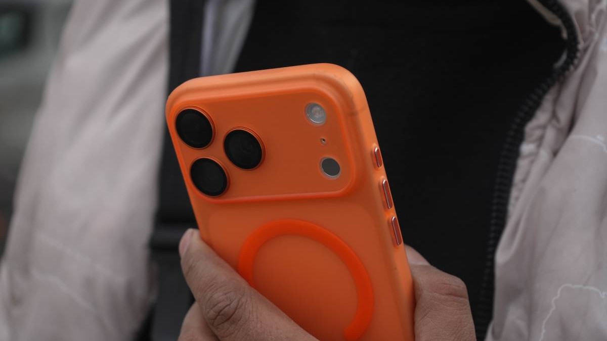 Un bărbat îine în mână un iPhone 17 Pro Max portocaliu.