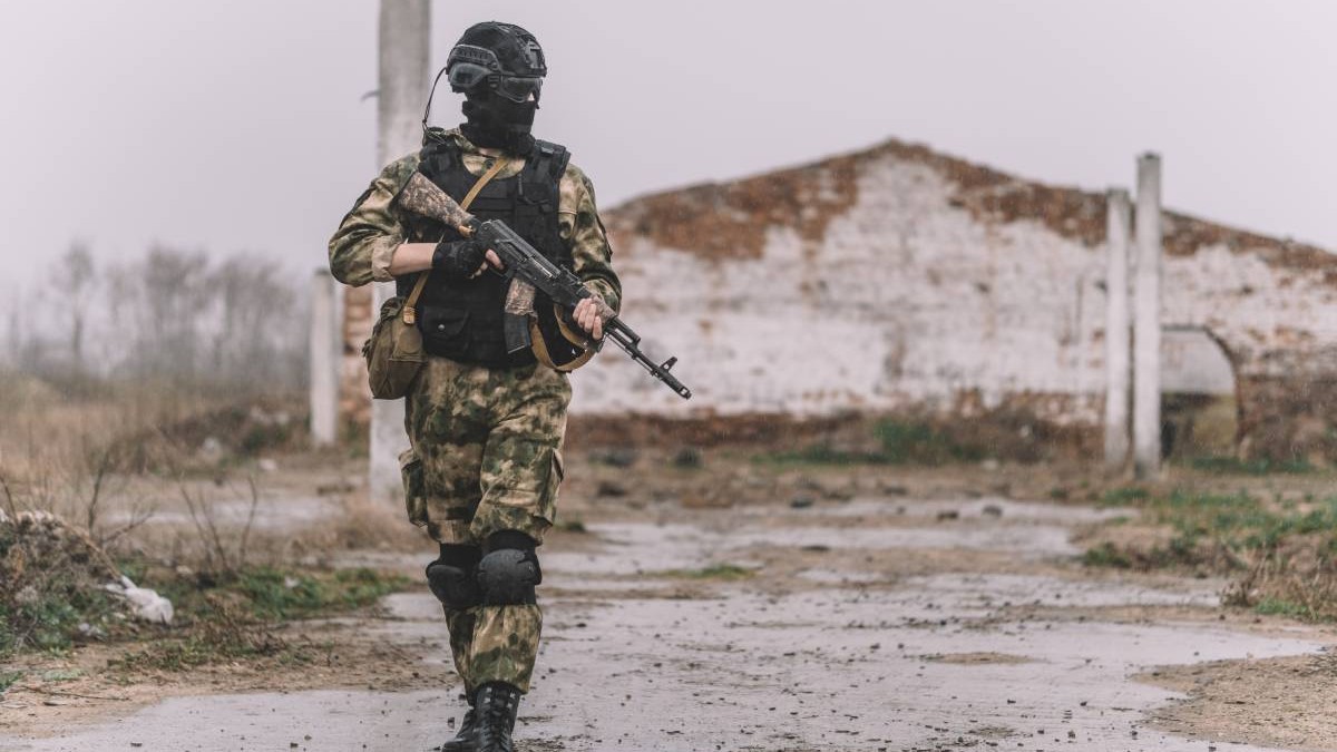 Un soldat îmbrăcat în costum de camuflaj cu o mitralieră în mână