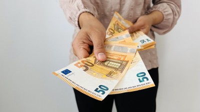 A,Woman,Hand,Offering,Two,50,Euro,Notes,And,Holding