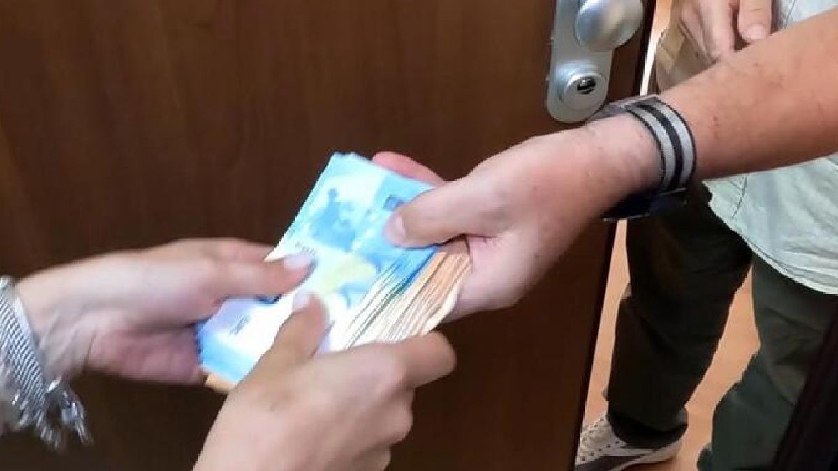 Imaginea arată în prim plan un bărbat și o femeie care țin în mâini același teanc de bancnote