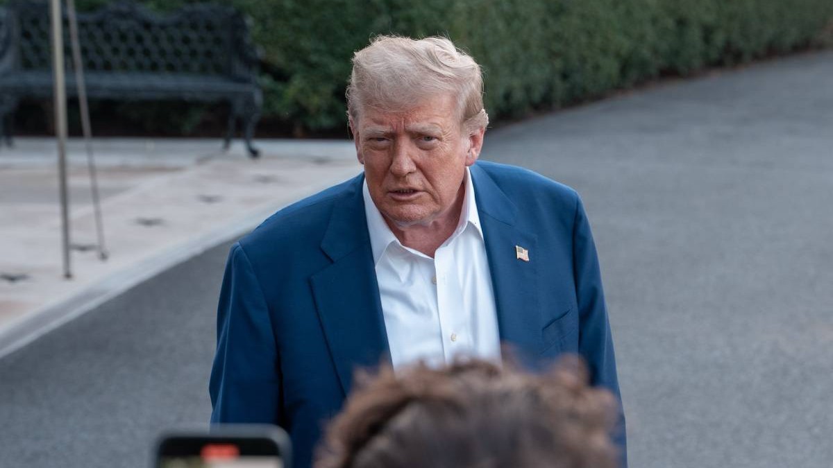 Președintele american Donald Trump, în timpul unei conferințe de presă, vorbește îmbrăcat la costum din fața intrării în Casa Albă, nu poarte cravată și este vizibil încruntat