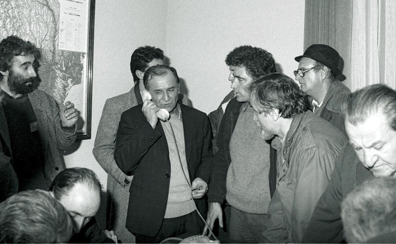 Ion Iliescu vorbind la telefon in sediul fostului Comitet Central al PCR, actualmente sediul MAI, pe 22 decembrie 1989, in timpul Revolutiei. In stanga imaginii apare Adrian Sarbu (cu barbă), viitorul proprietar al PRO TV. Foto: Agerpres