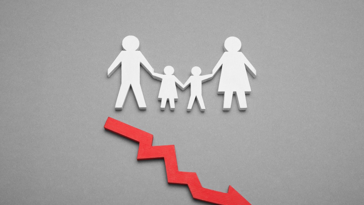 Imaginea ilustrează simbolic o familie reprezentată prin siluete albe, alături de o săgeată roșie orientată în jos, care sugerează scăderea populației. Compoziția este folosită frecvent pentru a ilustra teme precum declinul demografic, natalitatea redusă sau reducerea numărului de locuitori.