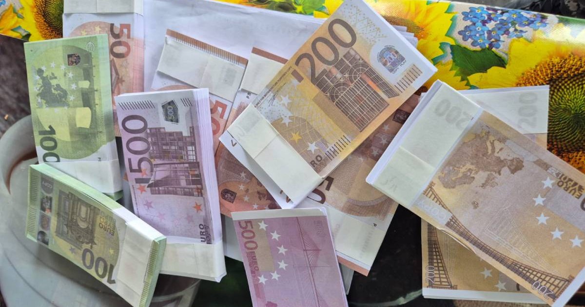 Un teanc de bancnote false de câte 100, 200 și 500 de auro, așezate pe o hârtie albă, pusă pe masă