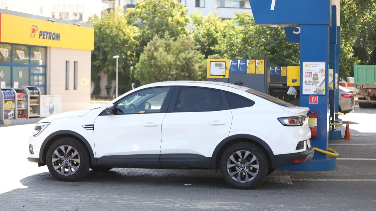 Imaginea prezintă un autoturism SUV coupe alb oprit la pompa unei stații de carburanți Petrom.