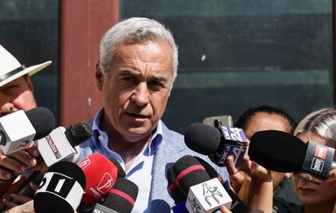 Călin Georgescu vorbește cu jurnaliștii la ieșirea din Parchet. e îmbrăcat cu un costum și are o figură gravă