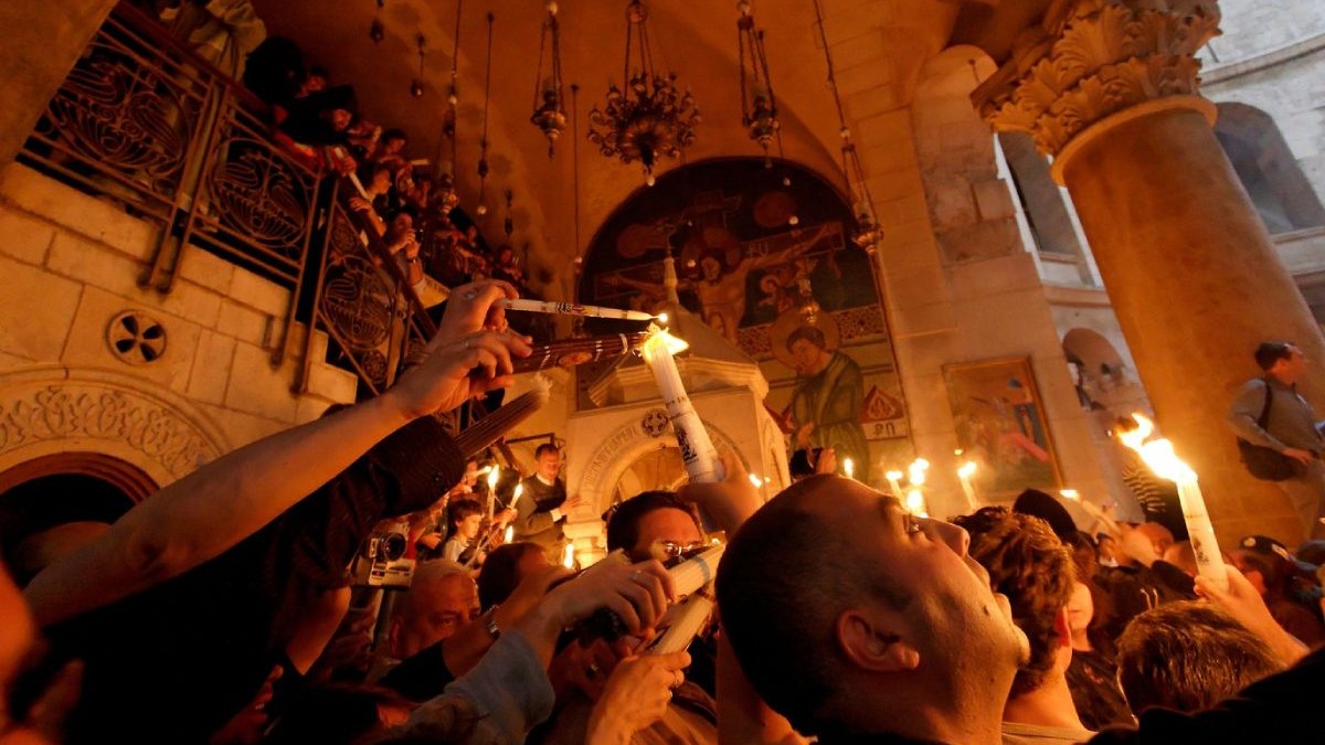 Credinciosi in biserica cu lumânări aprinse iau lumina Sfantă de PAște