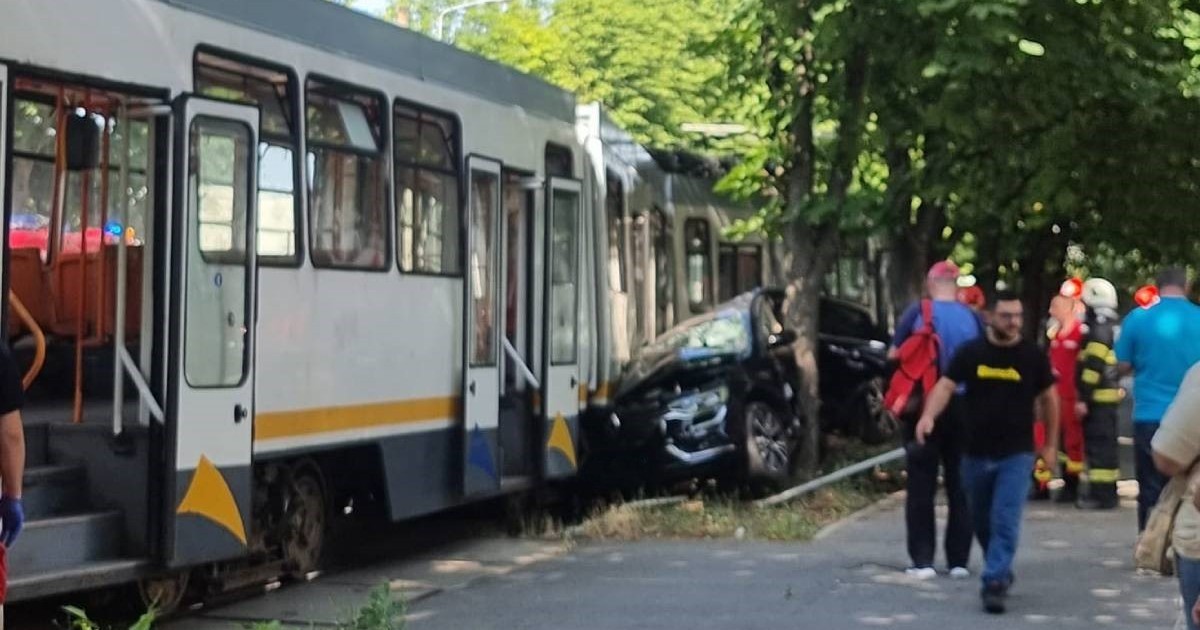 Imagine cu mașina strivită. Este vorba despre un Renault negru, iar în stânga se află tramvaiul
