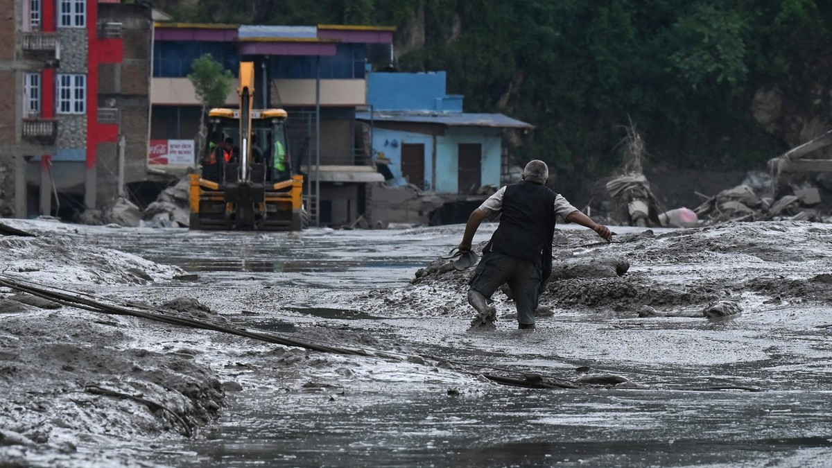 Un locuitor merge pe o stradă acoperită de noroi în urma inundațiilor fulgerătoare și a unei alunecări de teren din Devighat, în districtul Nuwakot din Nepal, pe 26 august 2026