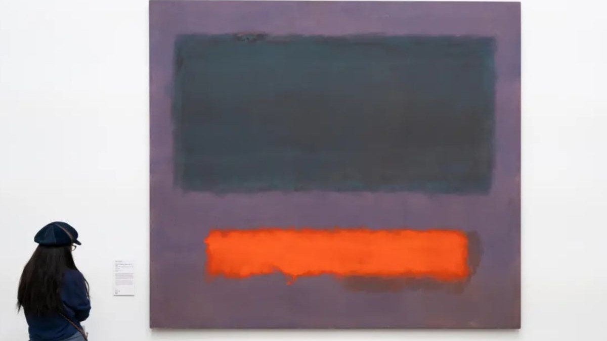 O tânără fotografiată cu spatele privește tabloul „Grey, Orange on Maroon, No. 8”, pictat de Mark Rothko în 1960, și expus la muzeul din Olanda