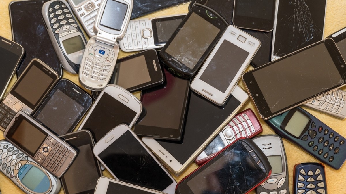 Mai multe telefoane vechi și uzate sunt puse grămadă pe un birou