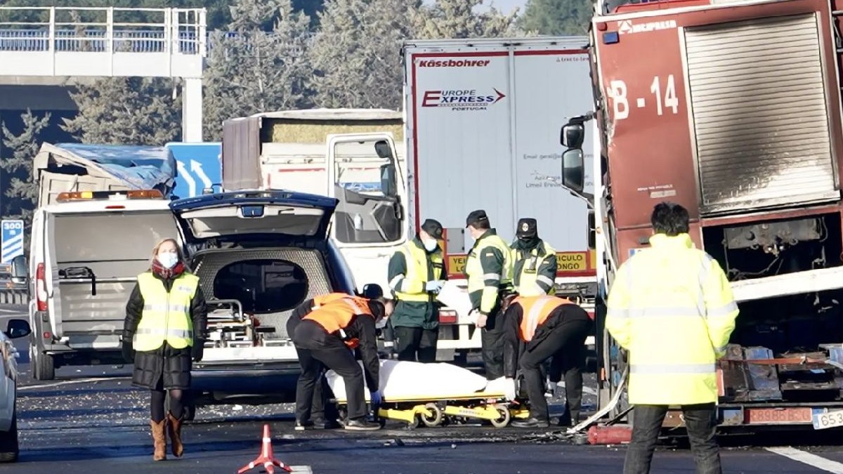 Imaginea prezintă echipe de intervenție în caz de urgență, îmbrăcate în veste de înaltă vizibilitate, care gestionează un accident rutier cu mai multe vehicule pe o autostradă