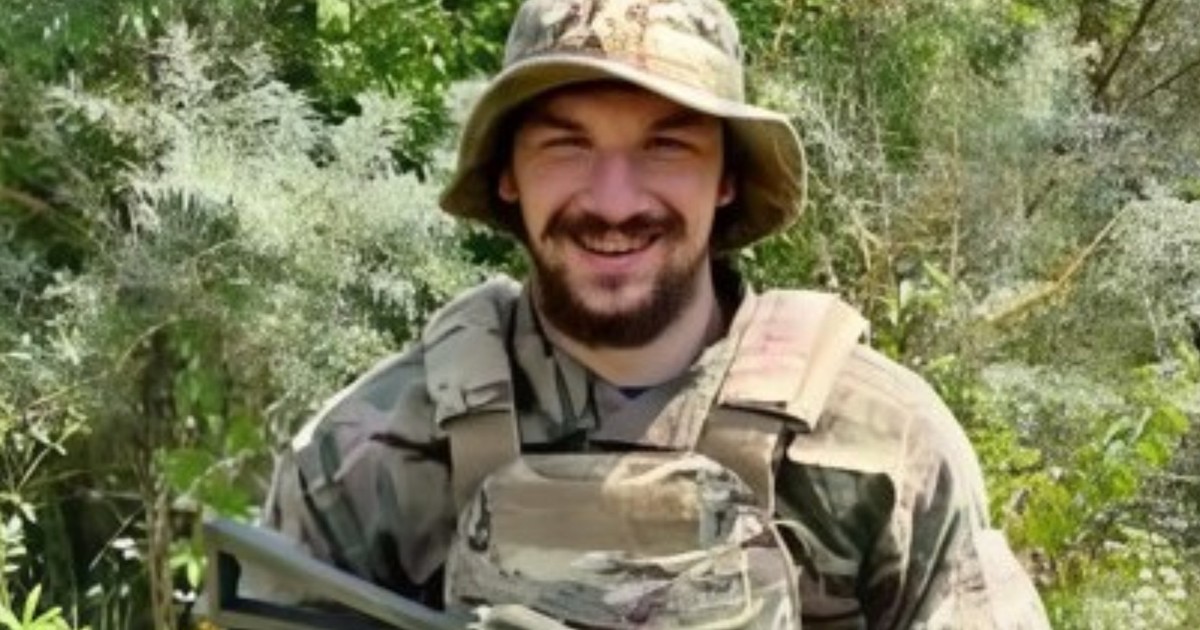 un tânăr din Ucraina ține o armă în mână și zâmbește