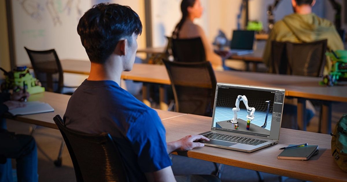 Un student lucrează pe un laptop în sala de clasă plină de bănci și de alți colegi.