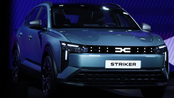 Un autoturism Dacia model Striker, de culoare gri-albăstruie, expus în cadrul unei prezentări pe un fundal iluminat în nuanțe de albastru. 