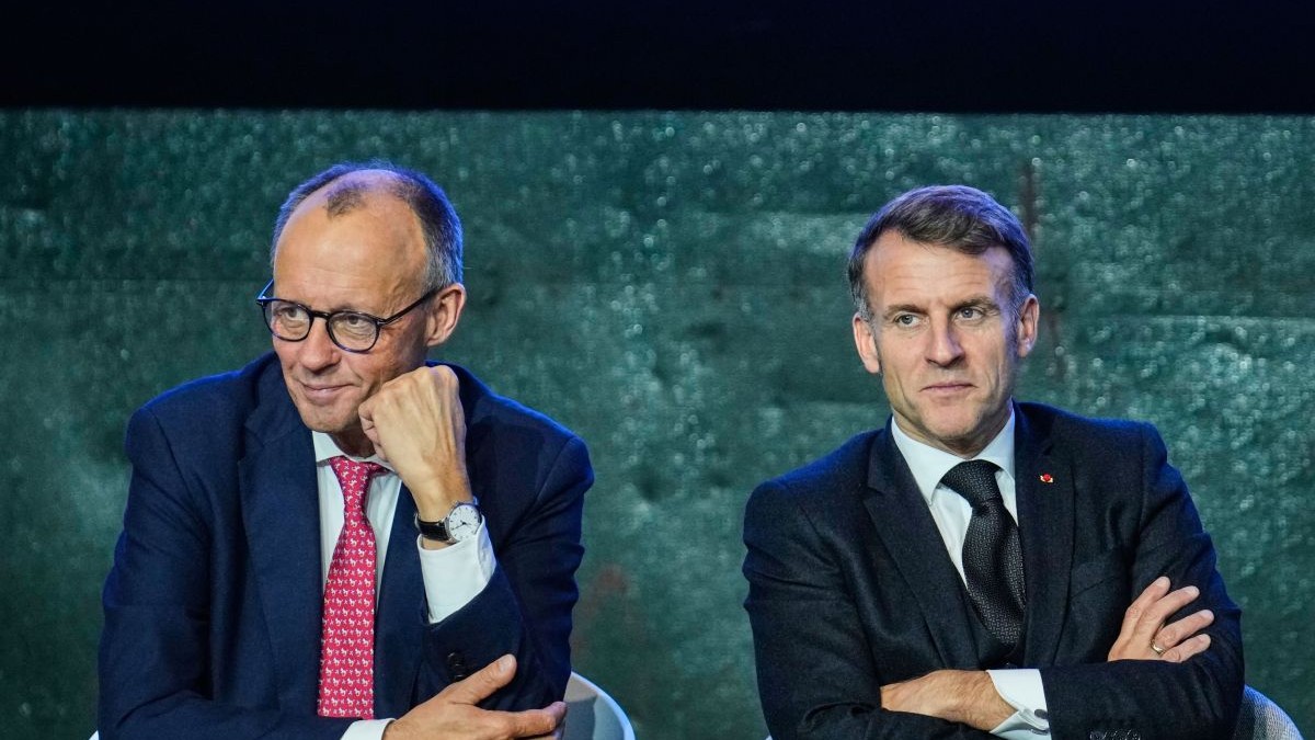 Friedrich Merz, cu pumnul la obraz și Emmanuel Macron, cu mâinile încrucișate, ascultă întrebarea unui reporter în timpul unui summit la Berlin, 18 noiembrie 2025