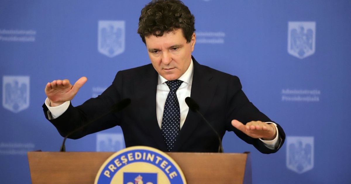 Președintele Nicușor Dan, îmbrăcat la costum, de la tribuna Președinției, vorbește și explică ceva arătând cu mâinile, iar în spate are un fundal albastru al Administrației Prezidențiale, București, 22 octombrie 2025