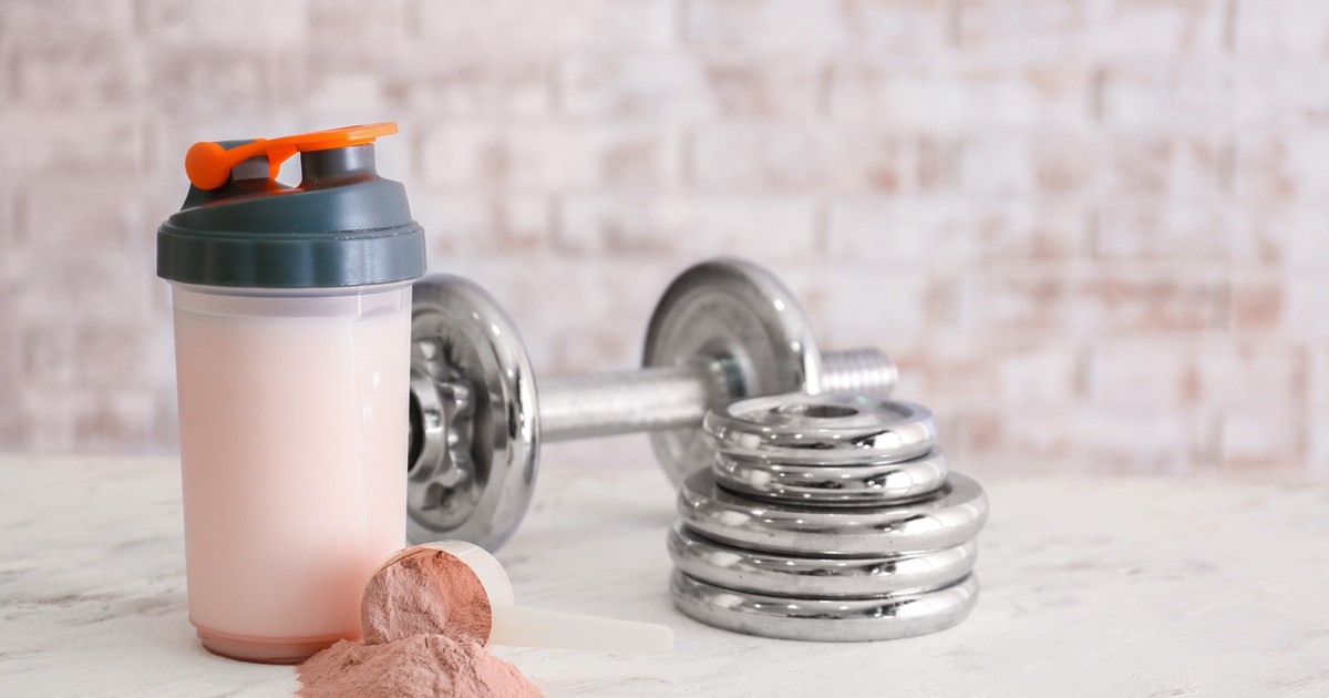 Ce sunt shake-urile proteice - Imagine cu un recipient în care a fost preparat un shake proteic, alături de o ganteră şi mai multe greutăţi