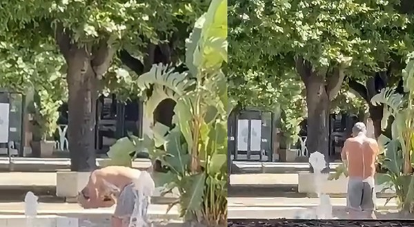 Un bărbat îmbrăcat în pantaloni gri se spală cu săpun într-o fântână arteziană, înconjurată de plante, din Italia.