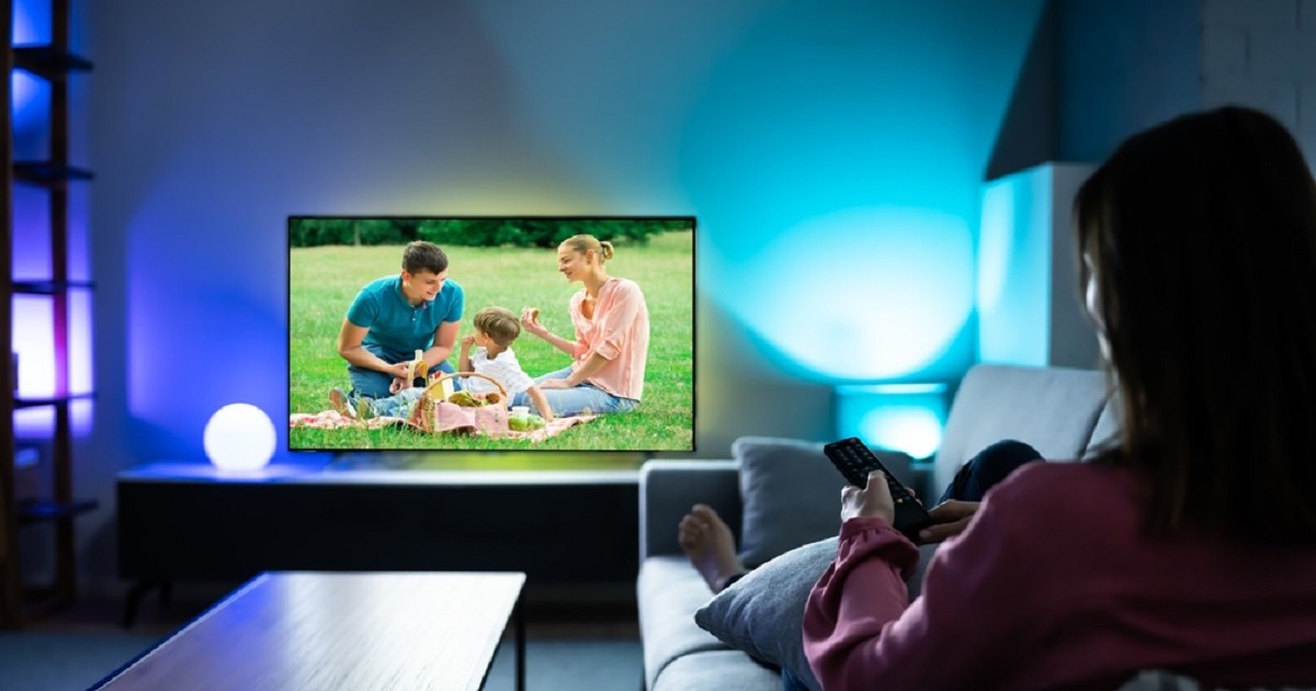 Televizoare Smart 4K ieftine de Black Friday 2025 - Imaginecu o femeie întinsă e canapea, care se uită la TV