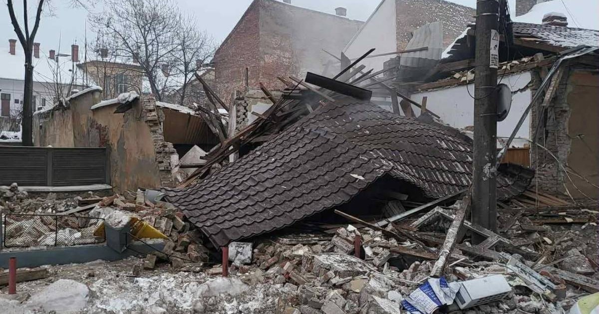 Imagine cu o cladire prabusita, au ramas doar ruine, acoperisul este cazut la pamant, se vede cum iese putin fum si sunt niste blocuri in spate, iarna. Cladirea Politiei din Lugoj s-a prabusit dupa o explozie, 14 ianuarie 2016