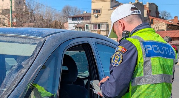 Un polițist verifică actele unui șofer dintr-o mașină neagră