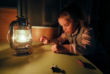 O fetiță se joacă cu plastilină la lumina unei lămpi, în apartamentul ei din Kiev Foto: EPA, 20 octombrie