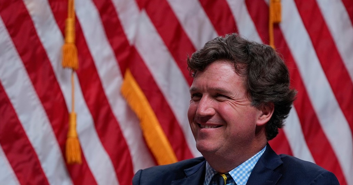 Tucker Carlson ascultă în timp ce candidatul republican la președinție, fostul președinte Donald Trump, vorbește în timpul unui spectacol Tucker Carlson Live Tour la Desert Diamond Arena, joi, 31 octombrie 2024, în Glendale, Arizona.