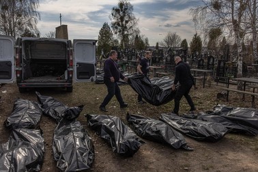 Voluntari cară trupurile găsite într-o groapă comună din Bucha, după plecarea forțelor ruse | Foto: EPA