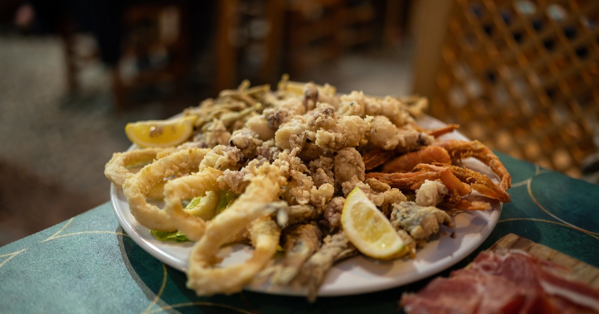 Imagine cu o farfurie plină cu calamar pane, midii pane și lămâie