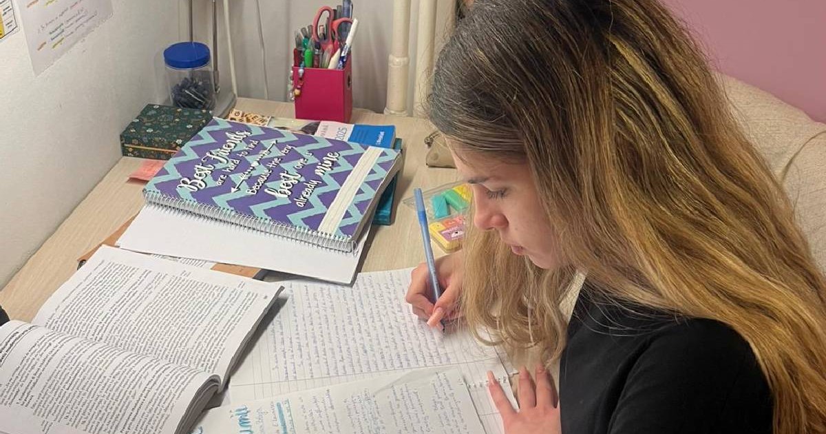 Tânără care scrie la birou un comentariu și învață pentru Bacalaureat