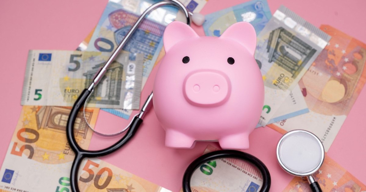 O pușculiță roz se află printre bancnote euro și un stetoscop.