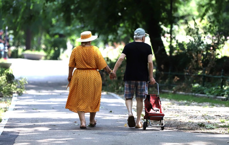 Doi pensionari imbracati frumos merg pe strada tinându se de mana