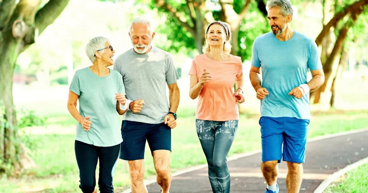 Două femei și doi bărbați care aleargă în parc, în echipament sportiv