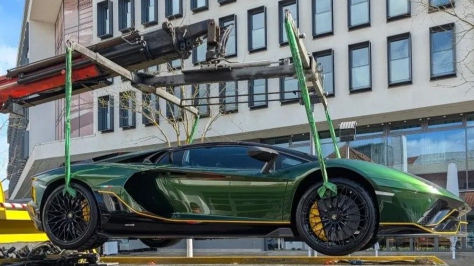 Lamborghini Aventador verde ridicat de o macara cu chingi speciale în fața unei clădiri