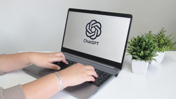 O femeie care scrie pe un laptop. Pe ecran este accesat ChatGPT