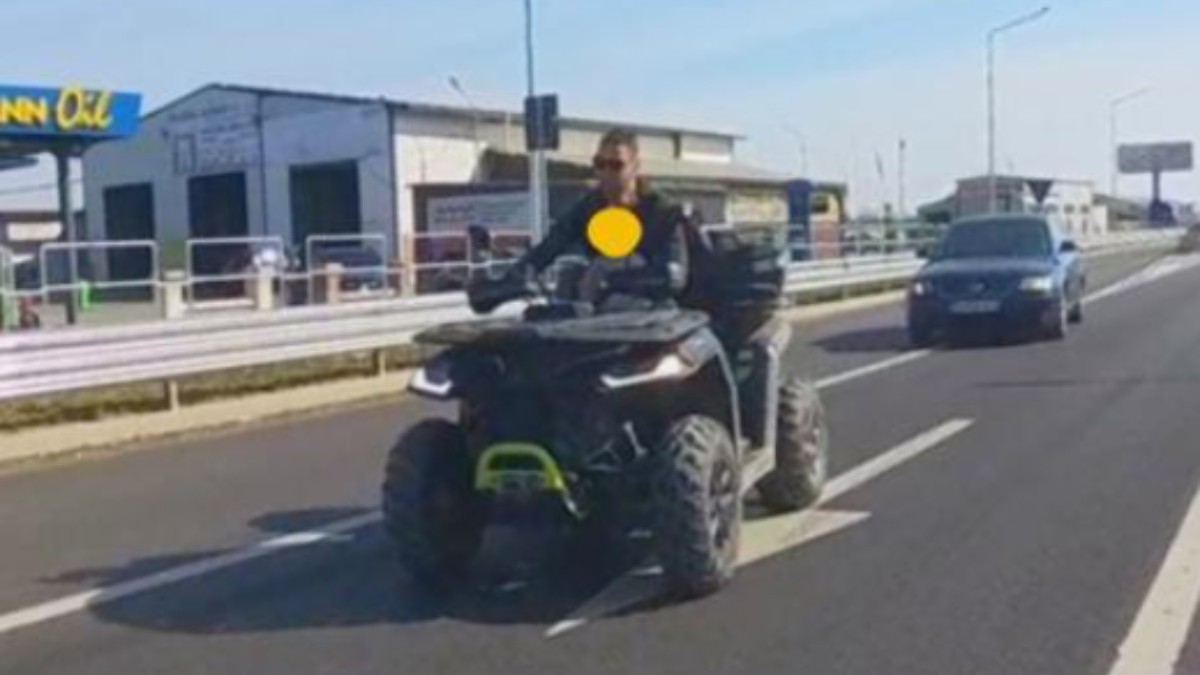 Un bărbat care merge pe un ATV, pe șosea