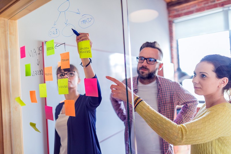 Business people meeting at office and use post it notes to share idea. Brainstorming concept. Sticky note on glass wall.