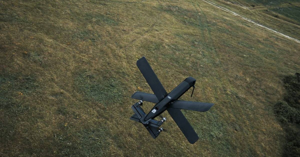 Drona Helsing HX-2 zboară deasupra unui câmp cu iarbă.